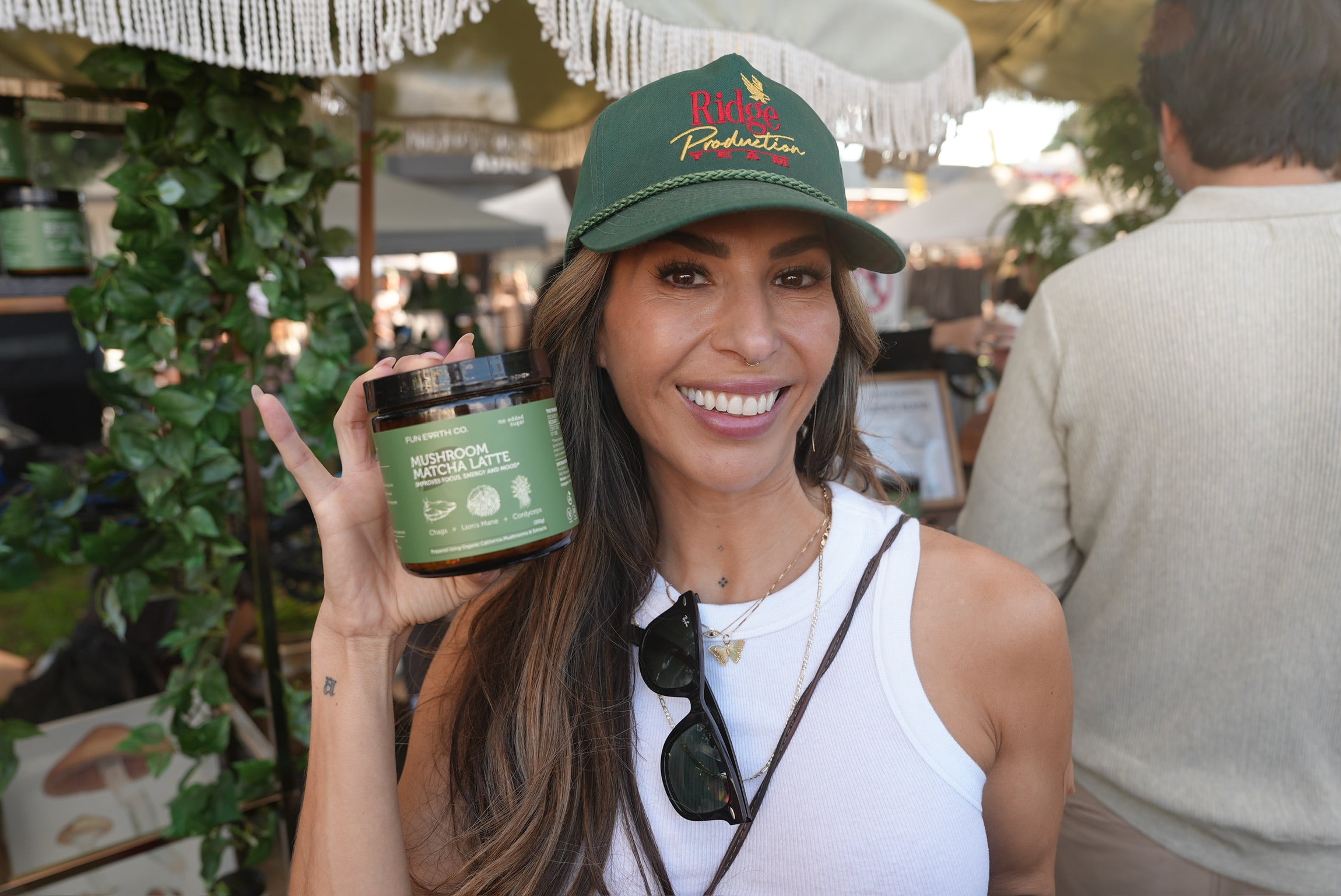 Woman holding a Fun Earth Mushroom Matcha Latte jar at a community market